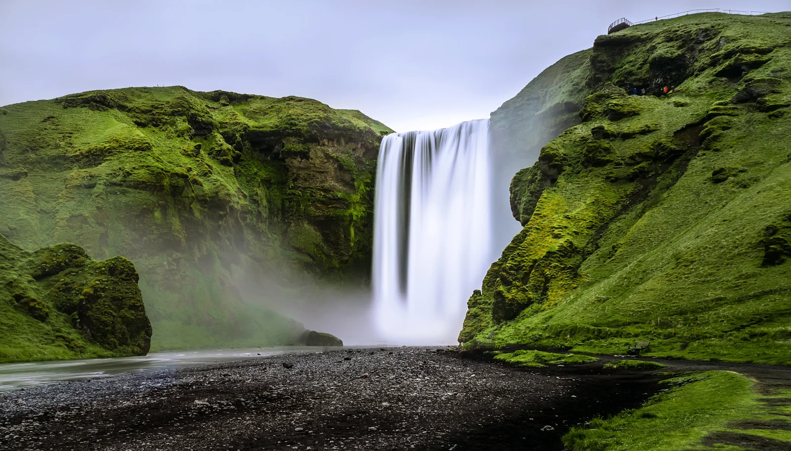 Skógafoss waterfall surrounded by green Icelandic cliffs